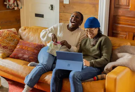 Two adult learners laughing together during an online lesson